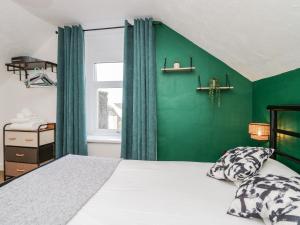 a bedroom with a green accent wall and a bed at 5C Queen Street in Whitehaven