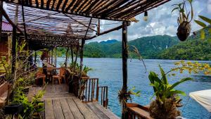 een steiger met een tafel en stoelen op het water bij The Jeti Mangrove - Ecolodge, Cottage, Restaurant & Kali Biru, Blue River in Rabia