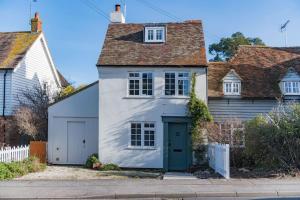 uma casa branca com uma porta verde numa rua em The Modern Cottage em Whitstable