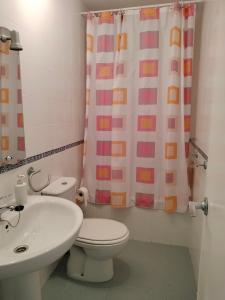 a bathroom with a toilet and a sink and a shower curtain at El mirador de la Ría in Isla Cristina