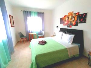 1 dormitorio con 1 cama grande con manta verde en Azimute Guest House en Aljezur