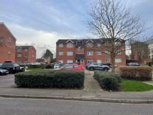 un coche rojo estacionado en un estacionamiento con edificios en Beautiful Peaceful Studio Flat en Waltham Abbey