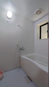 La salle de bains blanche est pourvue d'une baignoire et d'une fenêtre. dans l'établissement Ryukyo no Sato Auto Campsite - Vacation STAY 42105v, 