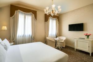 Habitación de hotel con cama, escritorio y lámpara de araña. en Residenza Venezia | UNA Esperienze en Venecia