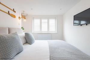 a white bedroom with a white bed and a window at Seascape in Whitstable