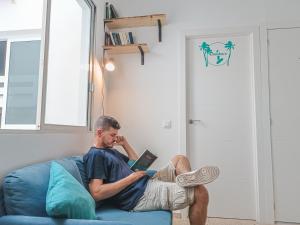 a man sitting on a couch reading a book at Daydream Medano Coliving in El Médano