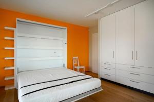 ein Schlafzimmer mit einem weißen Bett und einer orangefarbenen Wand in der Unterkunft Contemporary Penthouse with Cinema room and breath-taking Lakeview in Lausanne