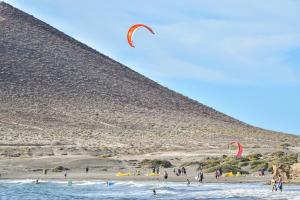 a group of people flying kites on the beach near the pyramid at Daydream Medano Coliving in El Médano