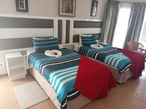 1 dormitorio con 2 camas y toallas. en THATCH HAVEN GUEST HOUSE, en Mahikeng