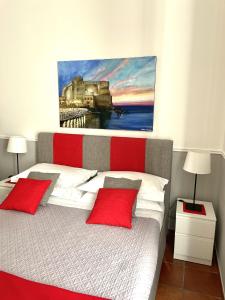 ナポリにあるResidenza Chiaiaのベッドルーム1室(赤い枕と絵画付)
