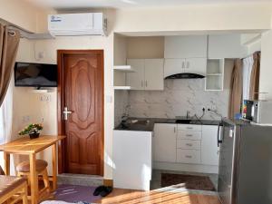 a kitchen with white cabinets and a wooden door at Shakya House in Pātan