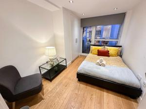 a bedroom with a bed and a chair and a window at Bright, spacious, 3-bedroom Emirates apartment with terrace in London