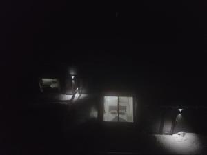 une personne debout dans une pièce sombre éclairée dans l'établissement Aurora View Lapland, Sky View Bedroom & Jacuzzi, à Kilpisjärvi