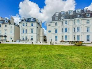 a large white building with a grass field in front at Sea View Apartment in Folkestone