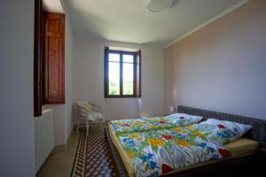 a bedroom with a bed with a colorful comforter and a window at App 1 per famiglie con splendida vista lago in Belgirate