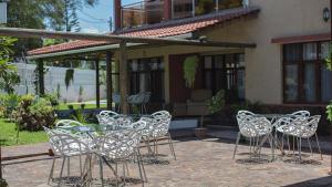 Kutenga Guest House في مابوتو: مجموعة من الكراسي وطاولة أمام المنزل