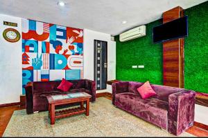 COLLECTION O HOTEL SKY INN في جايبور: غرفة معيشة مع كنبتين أرجوانيتين وتلفزيون
