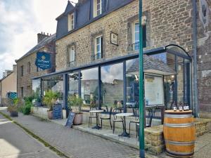 a cafe with tables and chairs in front of a building at Logis Le Prieuré in Locronan