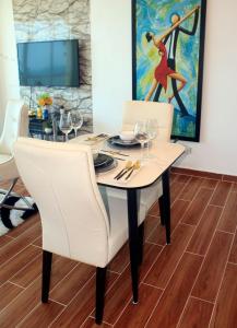 una mesa de comedor con sillas blancas y una pintura en Sturning Ocean View., en Santo Domingo