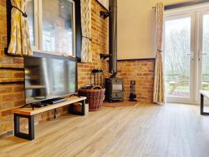 a living room with a television and a brick wall at The Stables, Wickham in Shedfield
