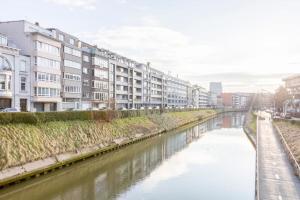 a river in a city with buildings and buildings at Luxury Leie View in Ghent