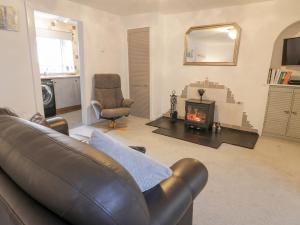 a living room with a leather couch and a fireplace at Rosalin Cottage in Irvine