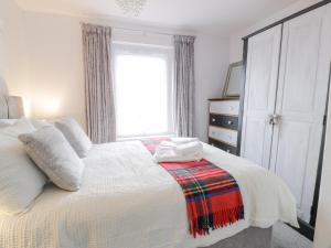 a bedroom with a white bed and a window at Rosalin Cottage in Irvine