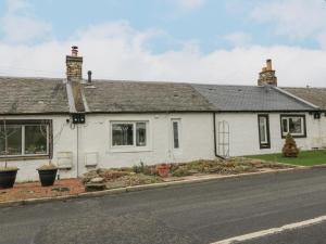 Ein weißes Haus an der Seite einer Straße in der Unterkunft Rosalin Cottage in Irvine