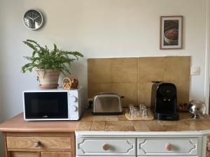 un four micro-ondes installé au-dessus d'un comptoir de cuisine dans l'établissement Rez de villa avec jardinet proche de la plage, à Hyères