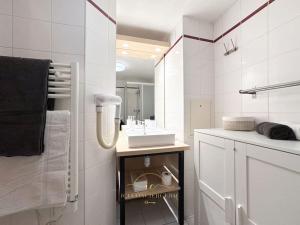 a white bathroom with a sink and a mirror at Le Cosy Saint-Cyr in Saint-Cyr-lʼÉcole
