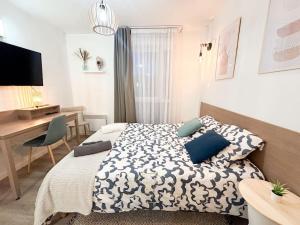 a bedroom with a bed with blue pillows and a desk at Le Cosy Saint-Cyr in Saint-Cyr-lʼÉcole