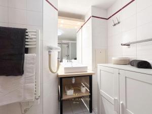 Baño blanco con lavabo y espejo en Le Cosy Saint-Cyr, en Saint-Cyr-lʼÉcole