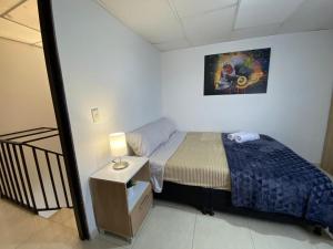 Dormitorio pequeño con cama y lámpara en comoda casa para descansar en Manizales