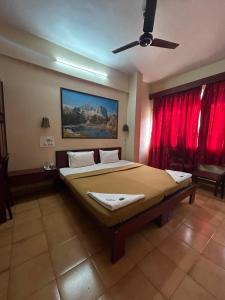 a bedroom with a large bed with red curtains at Hotel Prabha in Ratnagiri