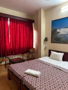a bedroom with two beds and a red curtain at Hotel Prabha in Ratnagiri +23 photos