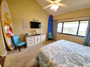 1 dormitorio con 1 cama, TV y tabla de surf en Summerhouse 433, en St. Augustine