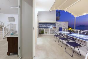 a kitchen with a long table with blue chairs at AMORE RENTALS - Villa Domus Franca in Massa Lubrense
