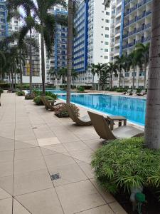 uma piscina com cadeiras, palmeiras e edifícios em King of kings em Manila