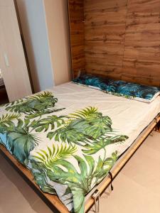 uma cama com um cobertor com plantas em RAINBOW FLAT- Monolocale luminoso em Milão