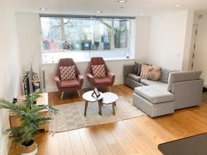 uma sala de estar com um sofá, cadeiras e uma mesa em Bright, spacious, 3-bedroom Emirates apartment with terrace em Londres