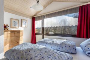 a bedroom with two beds and a window with red curtains at Ferienhaus Vorauf - Föttinger in Molberting