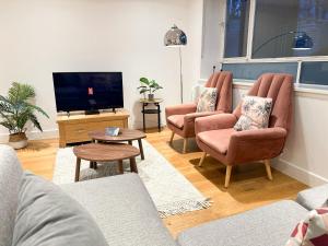 - un salon avec deux chaises et une télévision à écran plat dans l'établissement Bright, spacious, 3-bedroom Emirates apartment with terrace, à Londres