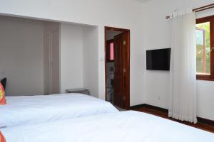 a bedroom with two white beds and a television at Kutenga Guest House in Maputo