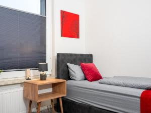 Un dormitorio con una cama con almohadas rojas y una mesa. en SR24 - Space mit Terrasse in Duisburg, en Duisburg