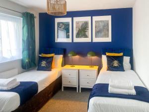 two beds in a room with blue walls at Phoenix House - 2 Double Bedroom House - Business and Corporate Travellers in Luton