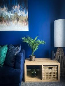 a blue living room with a couch and a table with a plant at Phoenix House - 2 Double Bedroom House - Business and Corporate Travellers in Luton