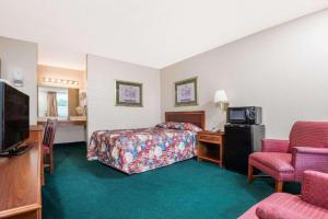 a hotel room with a bedroom with a bed and a tv at BlissPoint Inn Wabash in Wabash