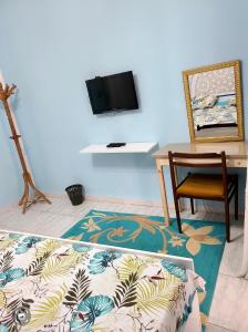 Habitación con silla, mesa y TV. en Maison D'hôte Dar Saida en El Kef
