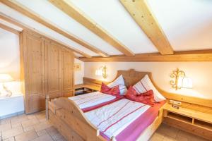 a bedroom with a wooden bed with red pillows at Landhaus Schenk Storchennest in Bad Hindelang
