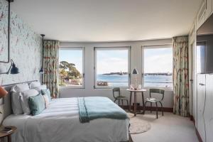 a bedroom with a bed and a table and windows at Castelbrac Hotel & Spa in Dinard +37 photos